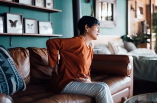 Woman suffering from a backache while sitting on a couch