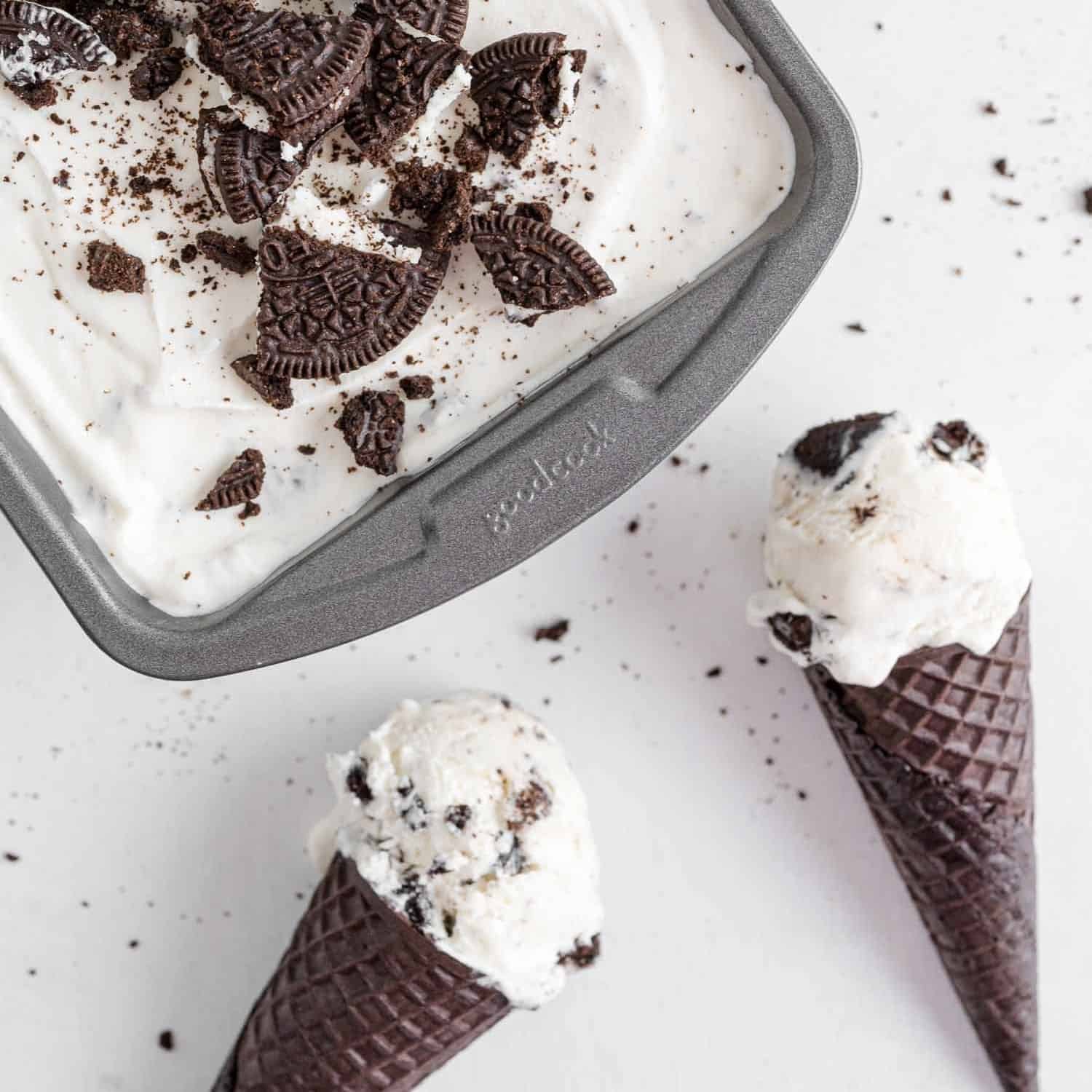 Oreo ice cream in a pan and in two chocolate cones.