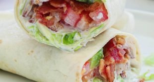 Two halves of an Easy BLT Wrap laying crosswise on top of each other on a white plate.
