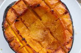 Half a Roasted Acorn Squash on a white plate.