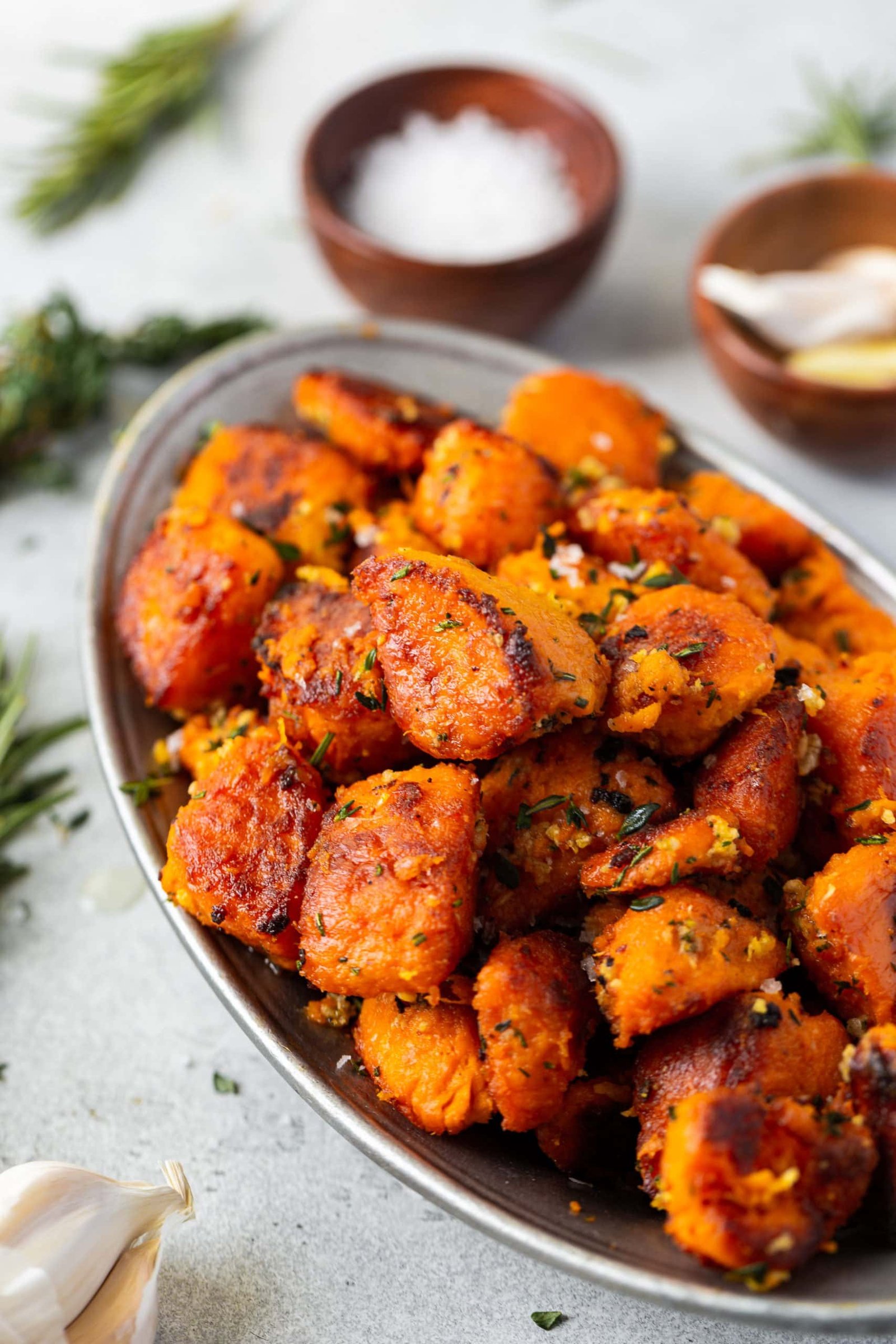 a photo of golden roasted sweet potato chunks piled high in an oval serving dish.