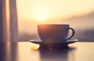 mug of coffee on table against the sunrise