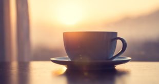 mug of coffee on table against the sunrise
