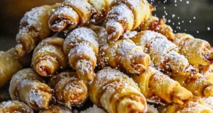 Plate of Apricot Rugelach being sprinkled with powdered sugar.