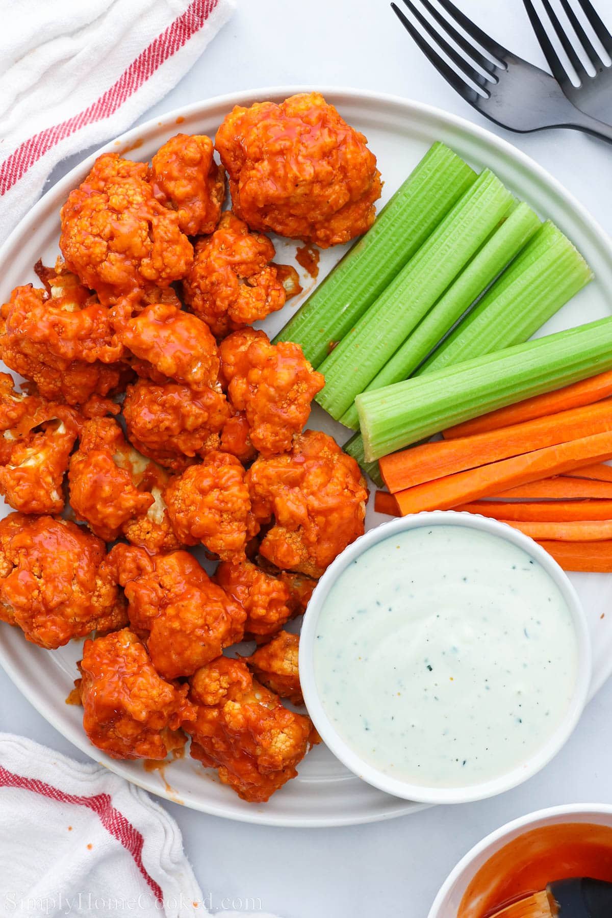 Air Fryer Buffalo Cauliflower on a plate with celery, carrot sticks, and ranch dressing.